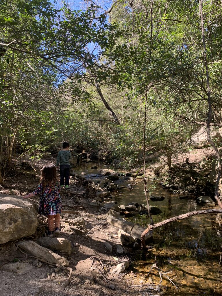 Two kids walking by creek at Great Hills trail